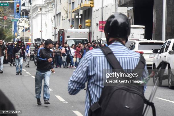 Member of armed groups that support the government called "Colectivos" runs towards the vehicle where a committee of Lawmakers drive away from the...