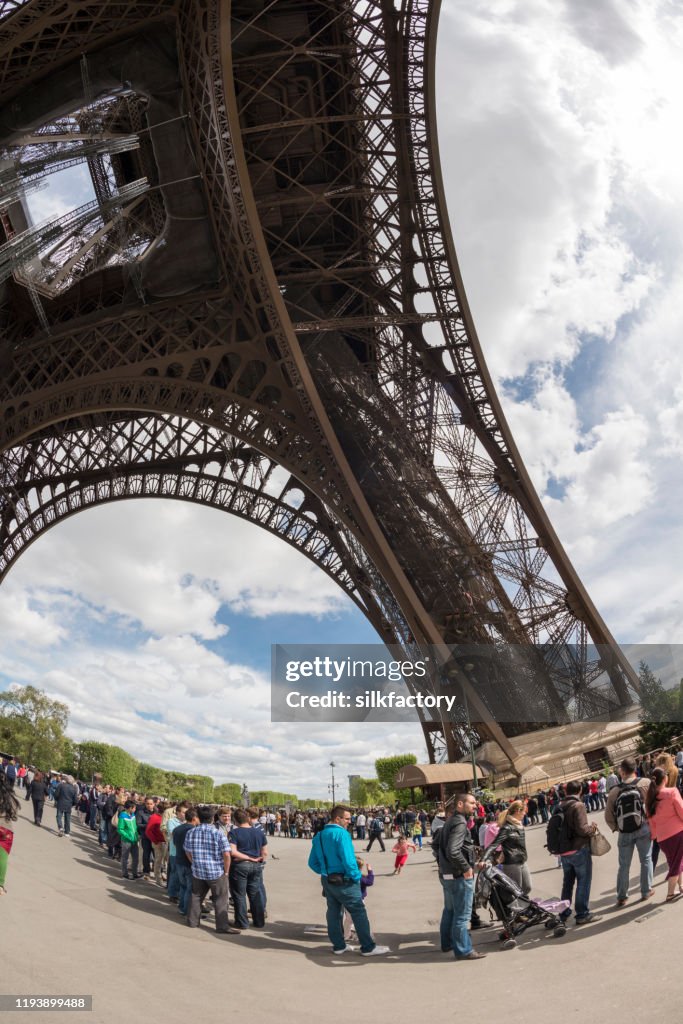 People standing in line to visit the Parisian Eiffel Tower in springtime