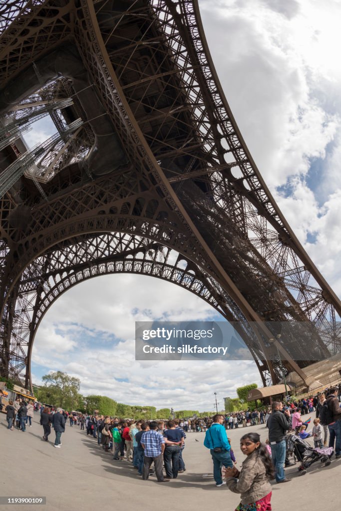 People standing in line to visit the Parisian Eiffel Tower in springtime