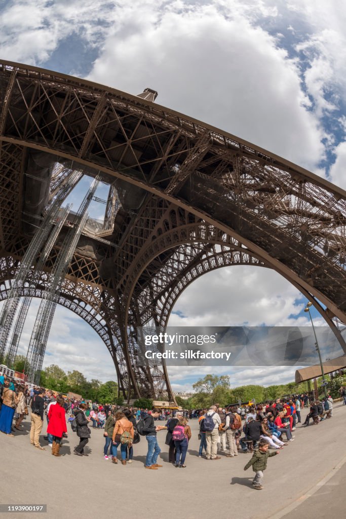 People standing in line to visit the Parisian Eiffel Tower in springtime