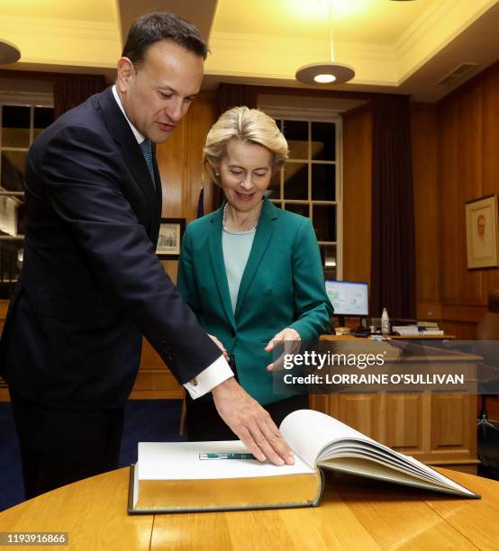 Ireland's Prime Minister Leo Varadkar stands with European Commission President Ursula von der Leyen as she signs the Visitors' Book during their...