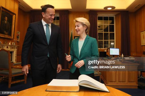 Ireland's Prime Minister Leo Varadkar stands with European Commission President Ursula von der Leyen as she signs the Visitors' Book during their...