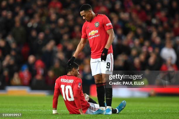 Manchester United's English striker Marcus Rashford is consoled by Manchester United's French striker Anthony Martial after seeming to pick up an...