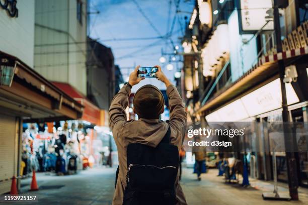 young asian male traveller photographing the vitality of local city street scene with smartphone while travelling in kyoto, japan - mobile billboard stock pictures, royalty-free photos & images