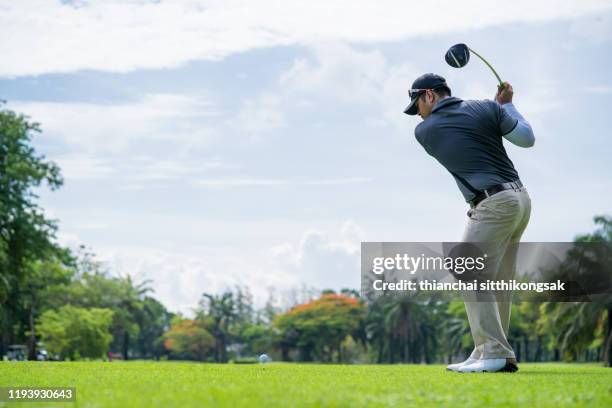 professional golf player is teeing off on green - golfschwung stock-fotos und bilder