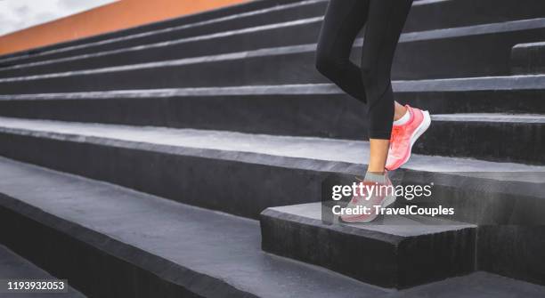 stairs climbing running woman doing run down steps on staircase. female runner athlete going down stairs in urban city doing cardio sport workout run outside during summer. activewear leggings and shoes. - down fotografías e imágenes de stock