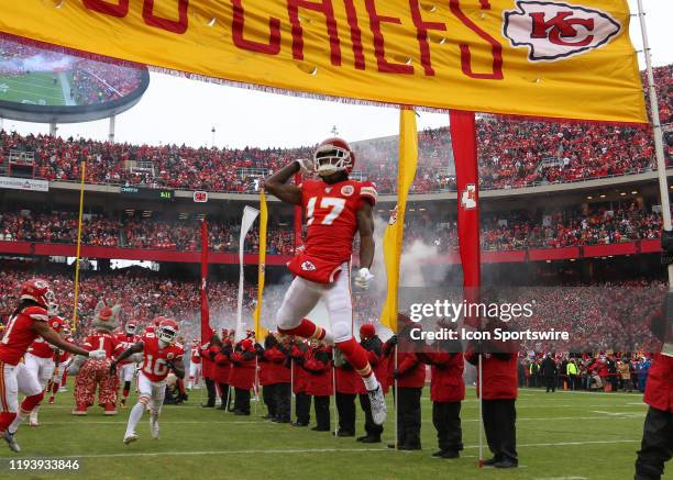 Kansas City Chiefs offensive tackle Eric Fisher leaps high to touch a banner while running onto the field before an NFL Divisional round playoff game...