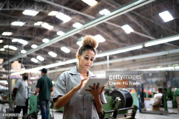 mulher que usa a tabuleta digital na indústria - manufacturing occupation - fotografias e filmes do acervo