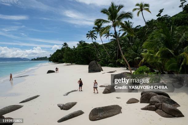 Picture taken on November 16 shows tourists walking on the beach with granite rocks on in Silhouette Island, the third largest island, Seychelles. -...