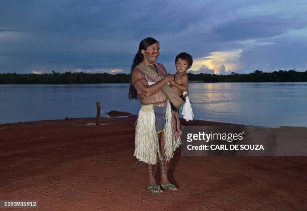 An indigenous woman and her child listen to their leader Cacique Raoni Metuktire of the Kayapo tribe, during a press conference in Piaracu village,...