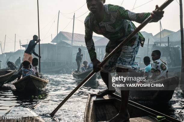 Picture taken on March 2, 2019 shows people steering boats on a waterway in the Makoko waterfront community in a polluted lagoon in Lagos, Africas...