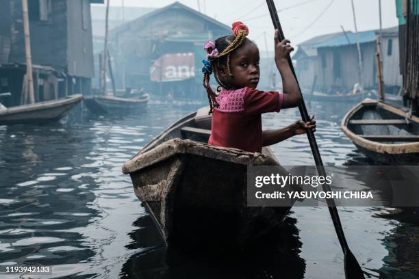 Picture taken on March 1, 2019 shows a girl steering a boat on a waterway in the Makoko waterfront community in a polluted lagoon in Lagos, Africas...