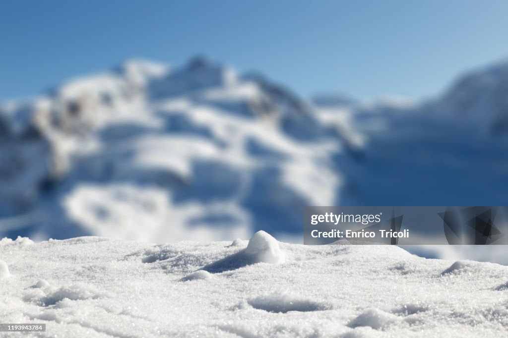 Foreground with fresh snow, with Swiss mountains in the blurred background.