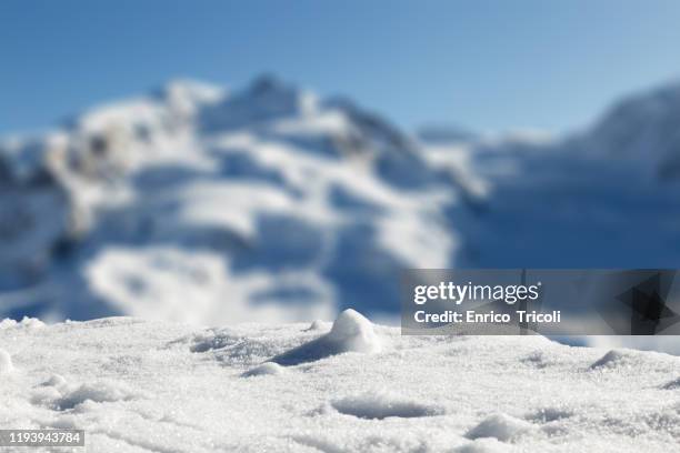 foreground with fresh snow, with swiss mountains in the blurred background. - mountain background stock-fotos und bilder
