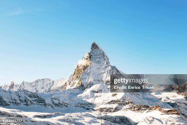 panorama of the matterhorn mountain range, covered with fresh snow, and blue sky in the cloudless background. christmas season, winter and ski slopes on the swiss alps. - matterhorn stock pictures, royalty-free photos & images
