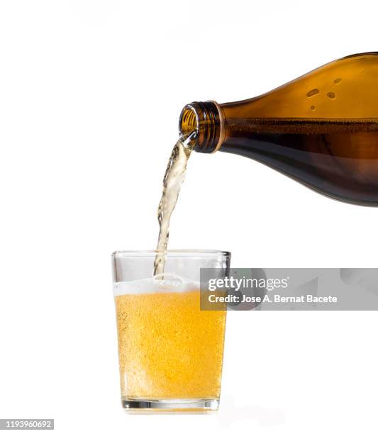 pouring glass of beer from bottle on a white background. - encher imagens e fotografias de stock