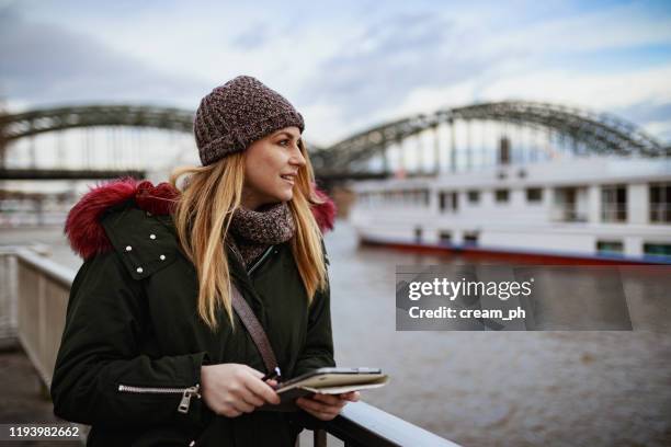 young woman using digital tablet near river on a winter day - cologne winter stock pictures, royalty-free photos & images