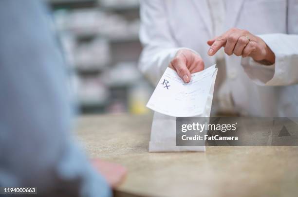 pharmacist holding out a packaged prescription stock photo - curing stock pictures, royalty-free photos & images