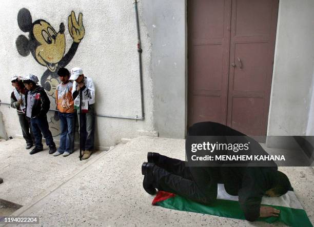 Palestinian man prays on his national flag after voting at a polling station 25 January 2006, in the West Bank village of Hawara south of Nablus, as...