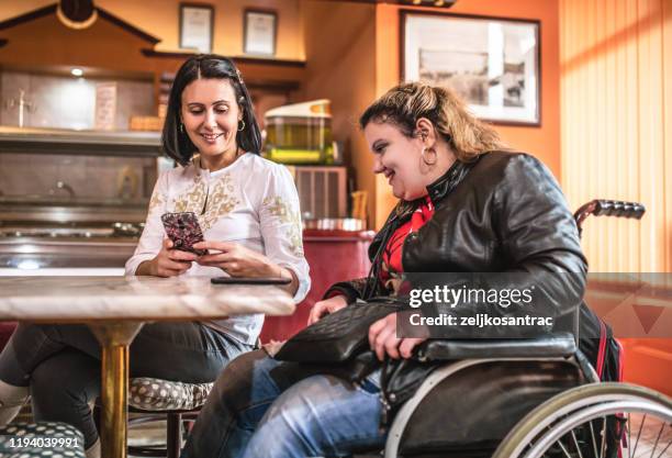 amis dans un café, la femme s'asseyant dans le fauteuil roulant - paraplegic woman photos et images de collection