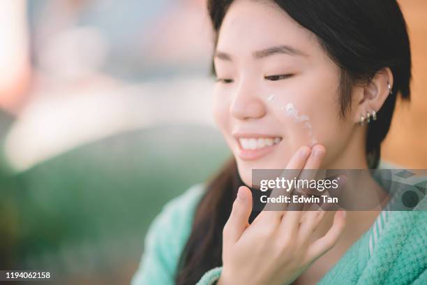 一個亞洲中國青少年女孩應用保濕霜的手和臉 - malaysia beautiful girl 個照片及圖片檔