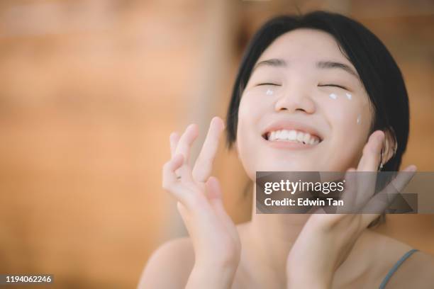 an asian chinese teenager girl applying skin lotion on her face outdoor - perfect girls body stock pictures, royalty-free photos & images