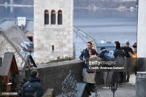 Tourists take photos on a cemetery in the town center on January 16, 2019 in Hallstatt, Austria. Hallstatt, known for its picturesque beauty and its...