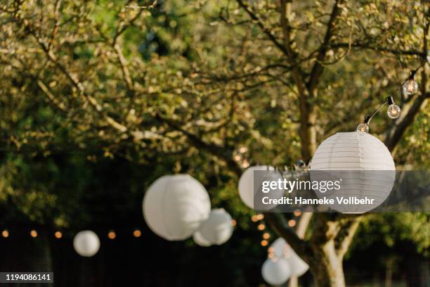 white lanters on a wedding in a garden - garland stock-fotos und bilder