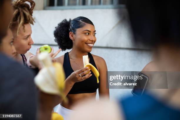 group of women eating banana after workout session - exercise and diet stock pictures, royalty-free photos & images