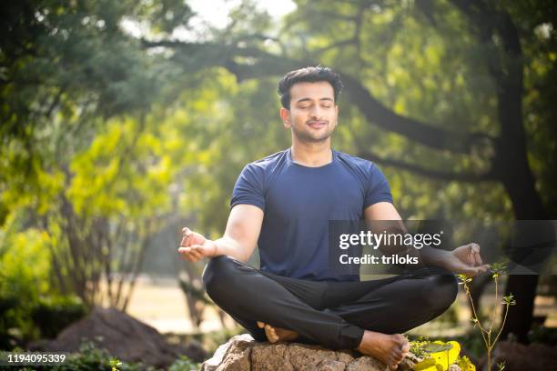 man meditating at park - mudra stock pictures, royalty-free photos & images