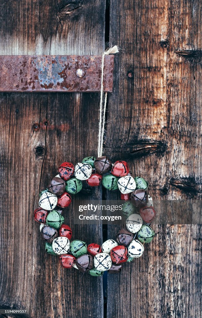 Christmas Bell Wreath On Distressed Old Wooden Brown Barn Door Metal Handle