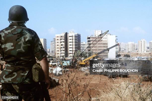 French soldier watches 25 October 1983 in Beirut the rubble of the -Drakkar- building which was destroyed by a suicide truck bomber overnight, 23...