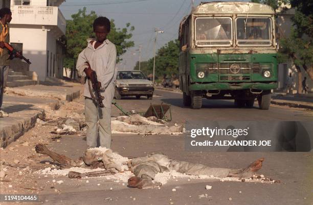 Somali young rebel points his arm on a Former President Siad Barre soldier victim laying dead, 30 January 1991 in a street of Mogadishu in Somalia....