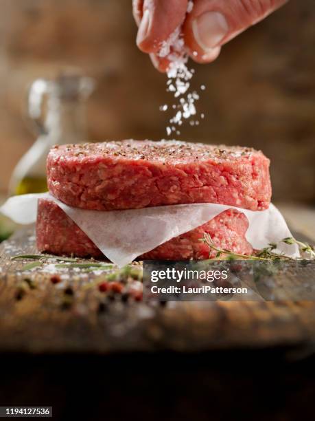 fresh ground hamburger patties - sprinkling salt stock pictures, royalty-free photos & images