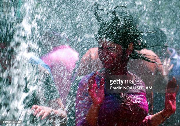 An Indian girl dances in artificial rain as she celebrates the festival of Holi, in Hyderabad on 03 March 2007. Holi, the festival of colours, is...