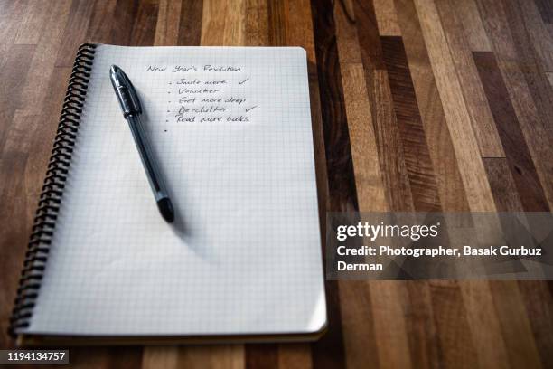 new year's resolution written on a notebook, and a pen on a wooden table - new years resolution stock pictures, royalty-free photos & images