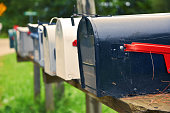 An isolated row of metal US mail boxes on wooden post in the countryside. Spider webs in one of them. Mail concept. New York City. United States