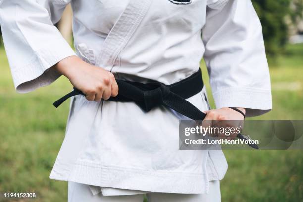 mujer luchadora apretando el cinturón de karate - women's judo fotografías e imágenes de stock