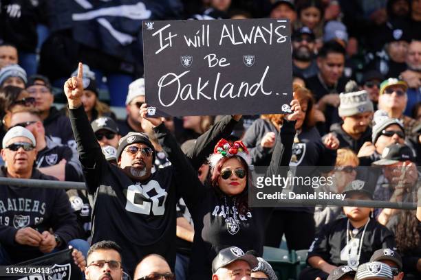Fans in the stands hold signs during the first half between the Oakland Raiders and the Jacksonville Jaguars at RingCentral Coliseum on December 15,...