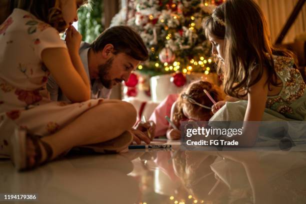 small cute girls writing letter to santa at home - father assistance - child writing letter to santa stock pictures, royalty-free photos & images