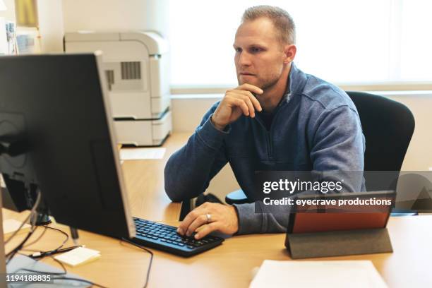 adult male athletic director at work with technology in office setting - co directors stock pictures, royalty-free photos & images