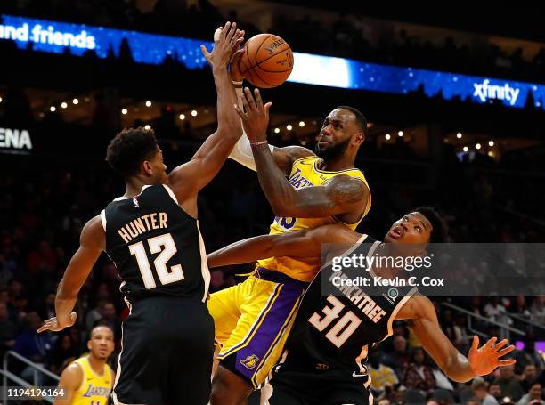 LeBron James of the Los Angeles Lakers drives against De'Andre Hunter and Damian Jones of the Atlanta Hawks in the first half at State Farm Arena on...
