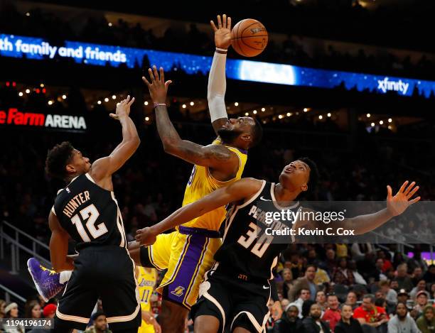 LeBron James of the Los Angeles Lakers drives against De'Andre Hunter and Damian Jones of the Atlanta Hawks in the first half at State Farm Arena on...