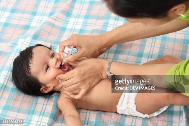administering oral poliovirus vaccine to infant - polio stockfoto's en -beelden