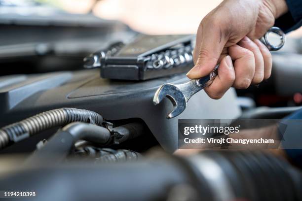 mechanic using laptop while examining car engine, car fixing with technology concept - car repair ストックフォトと画像