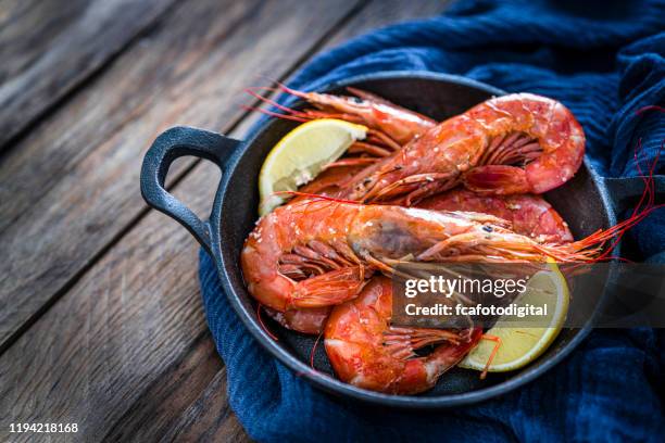 gamberi cotti in una padella in ghisa girata su un tavolo di legno. spazio di copia - shrimp foto e immagini stock