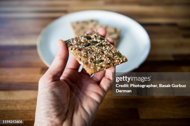 a hand holding a crispbread - crispbread crackers photos et images de collection