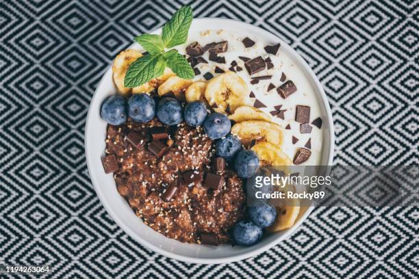 organic chocolate and buckwheat porridge bowl topped with banana, blueberries, kiwi and popped amaranth - buckwheat stock pictures, royalty-free photos & images