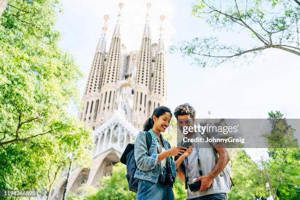 cheerful tourists checking smart phone near sagrada familia - sagrada familia barcelona stock pictures, royalty-free photos & images