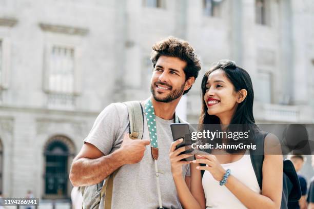 pareja turística que utiliza el teléfono inteligente para obtener orientación en barcelona - mirar alrededor fotografías e imágenes de stock